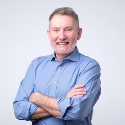 Senior man in blue shirt smiling broadly and looking at camera with confidence. Positive facial emotion